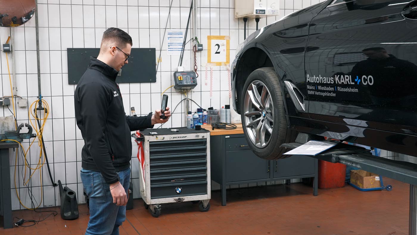 Ein Mitarbeiter scannt einen Reifen mit Tire Scan Mobile direkt am Fahrzeug.